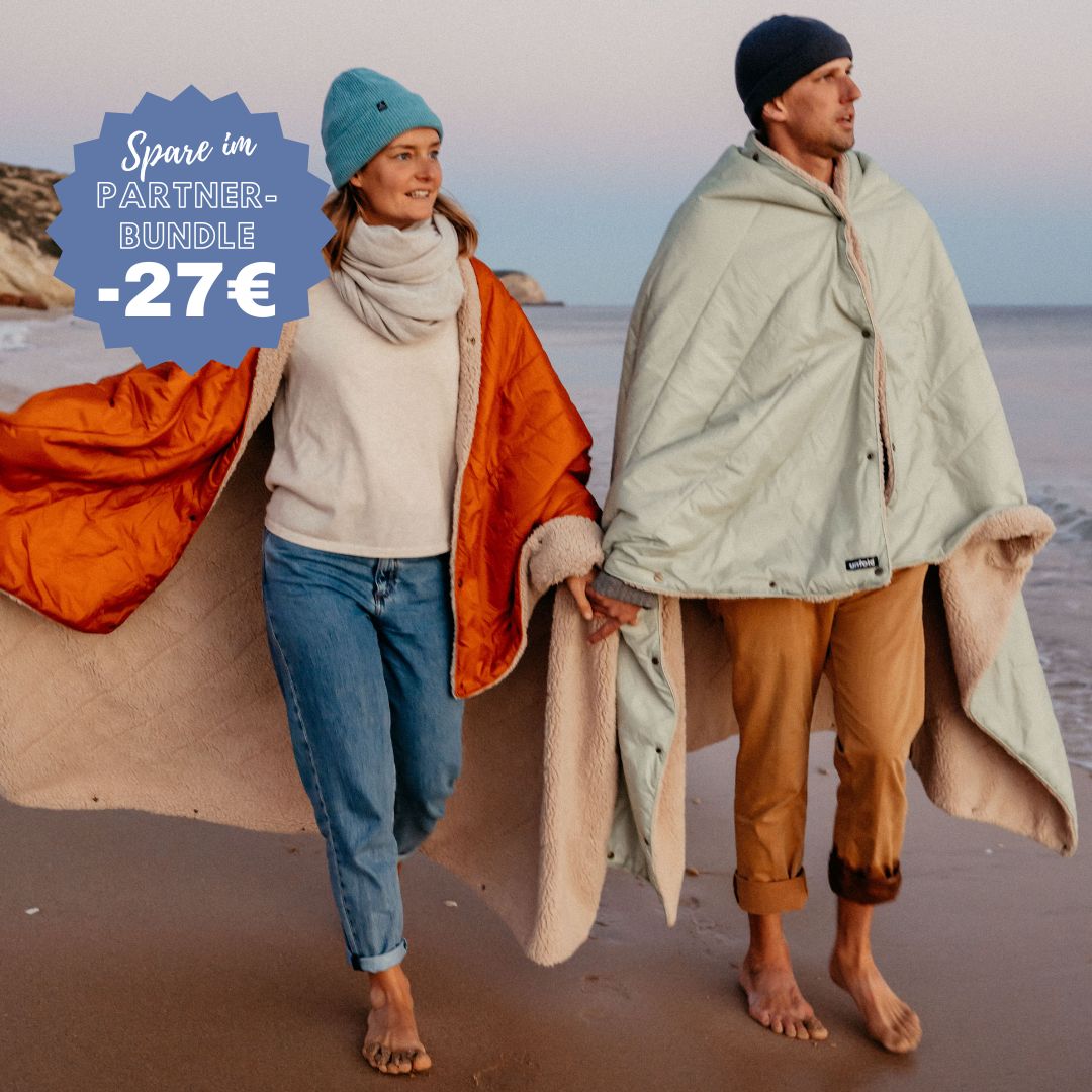 Paar am Strand laufend mit Decken eingewickelt