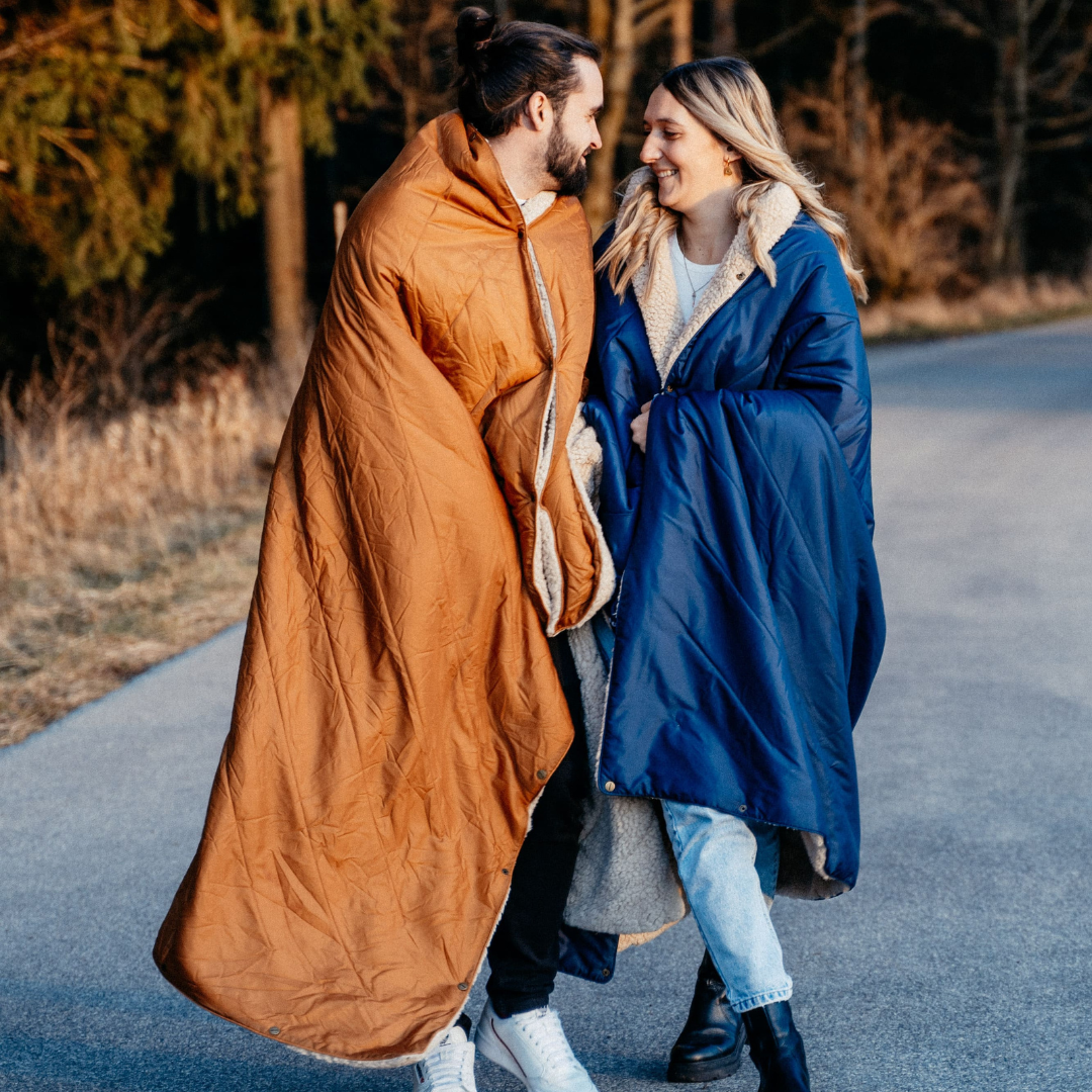 Paar am Waldrand mit blauer und hellbrauner Decke eingwicklt